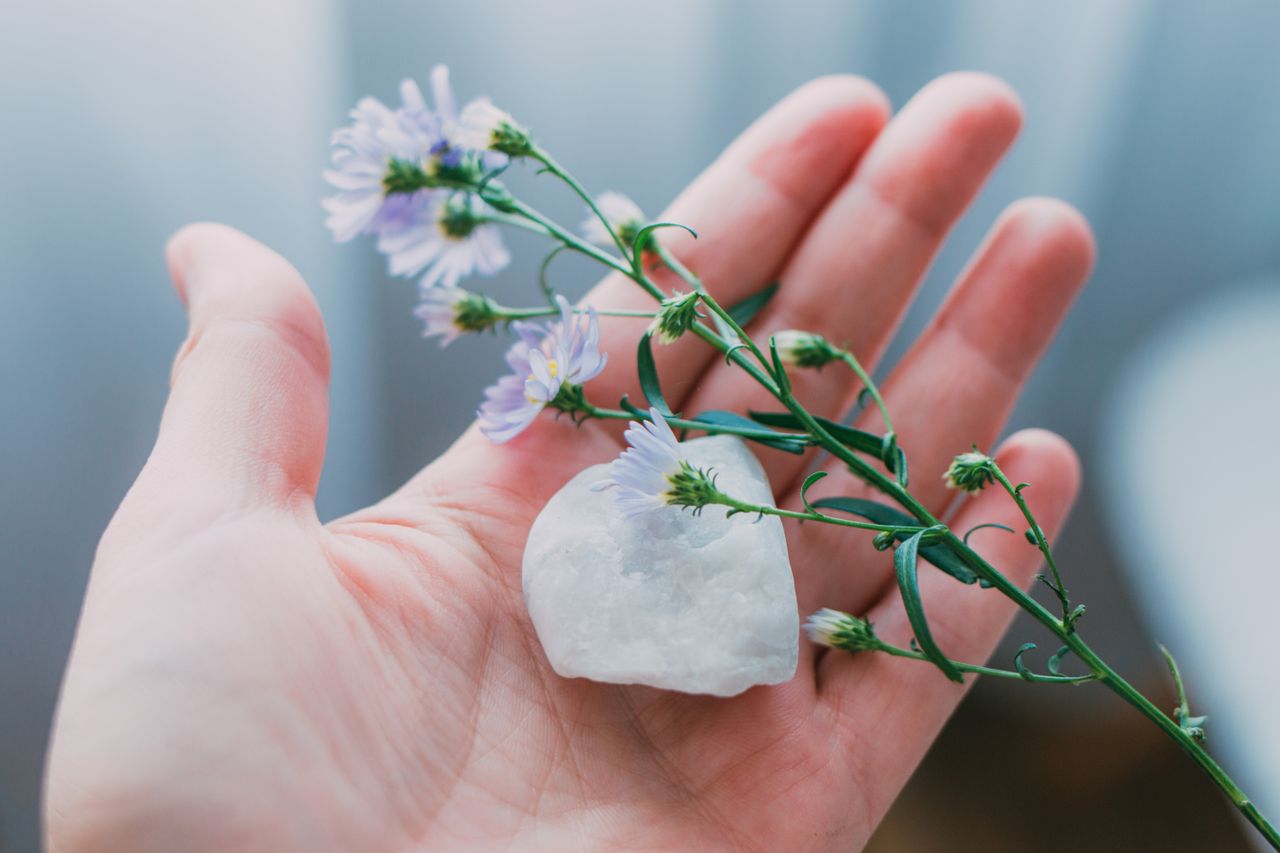 The Art of Drawing Readers In: Your attractive post title goes here Close-up of clear quartz and purple flowers gently held in a hand, symbolizing beauty and tranquility.